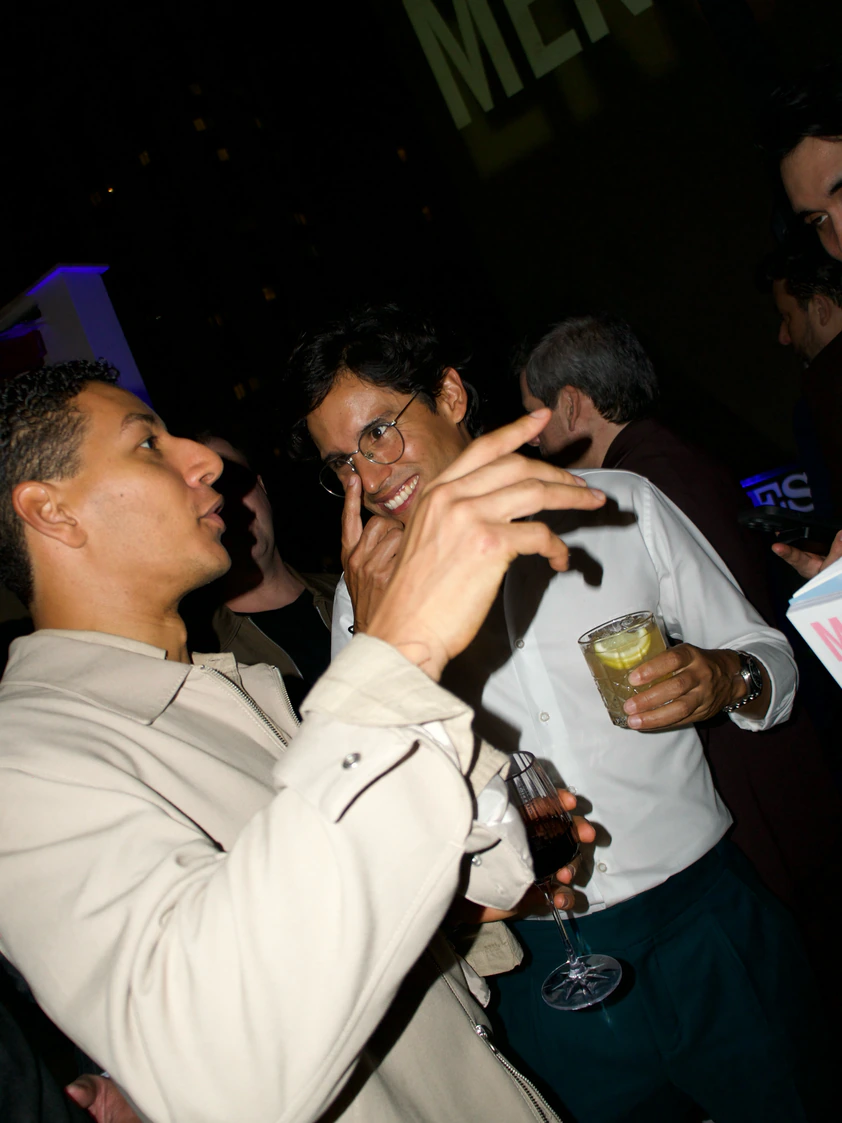Convidados conversando com drinks em evento noturno no rooftop